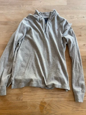 Polo Ralph Lauren hoodie  - Snygg grå långärmad tröja från Polo Ralph Lauren med halvzip och liten broderad logga på bröstet. Tillverkad i mjukt bomullsmaterial och har en avslappnad passform. Perfekt till lager-på-lager och enkel att matcha.