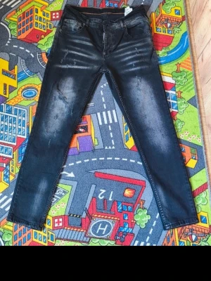Svarta slim fit jeans med slitningar - Snygga svarta slim fit jeans med diskreta slitningar och blekta detaljer framtill. Klassisk femficksmodell med dragkedja och knapp. Jeansen har en modern look och passar perfekt till en streetwear-stil.