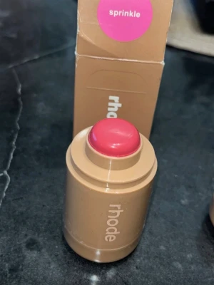 Rhode krämrouge stick Sprinkle - Krämrouge i stickformat från Rhode i färgen Sprinkle, en fräsch rosa nyans. Kommer i en beige cylinderformad hylsa med tydlig logga. Enkel att applicera direkt på kinderna för en naturlig glow och smidig att ta med i väskan.