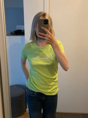 Limegrön t-shirt från Benetton - Limegrön t-shirt från Benetton i storlek M med vitt tryck på bröstet i skrivstil. T-shirten har rund halsringning och korta ärmar. 20 kr!