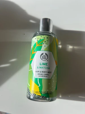 Lime & Matcha Hair & Body Mist - Fräsch hår- och kroppsmist från The Body Shop med doft av lime och matcha. Flaskan är i hård plast med färgglad grön, gul och vit etikett och har ett silverfärgat spraylock. Innehåller 150 ml och ger en uppfriskande känsla.