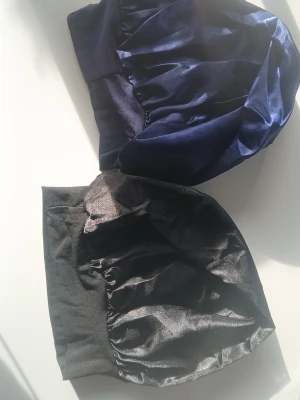Två satindukar i svart och marinblå - Säljer två satindukar i olika färger, en i svart och en i marinblå. Perfekta för att skydda håret under natten eller som accessoar. Båda är mjuka och har en glansig finish som ger en lyxig känsla.