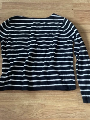 Randig tröja med broderade läppar - Säljer en svart och vit randig tröja med långa ärmar. Tröjan har coola broderade detaljer som röda läppar, stjärnor och en krona framtill. Perfekt för dig som vill sticka ut lite extra! Materialet känns mjukt och skönt mot huden.