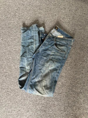 Ljusblå raka jeans från Lee - Säljer ett par ljusblå jeans från Lee med klassisk femficksdesign och raka ben. Jeansen har Lee-logga på bakfickan och är tillverkade i denim. Perfekta för en avslappnad och trendig stil.