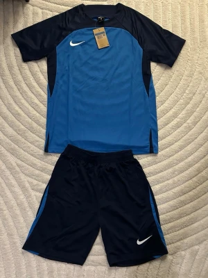 Nike blått fotbollsställ - Blå och Mörkblå träningset från Nike. Storlek M, helt ny och Oanvänd. Perfekt nu under sommarn, träning och annat. Fraktas inom 24 timmar efter köp📦🚛