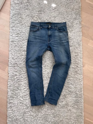 Blå slim fit jeans från Nudie - Snygga blå slim fit jeans från Nudie i storlek W32 L32 men jag skulle säga att längden inte är true to size. Skicka om du är osäker så svarar jag på alla frågor! Modell: High Kai. 