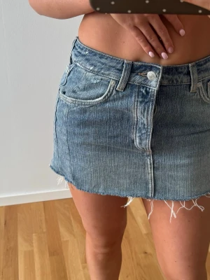 Blå jeanskjol med rå kant - Säljer en kort jeanskjol i klassisk blå denim med rå, fransig kant nertill. 
