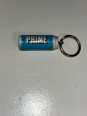 Blå PRIME nyckelring - Säljer en blå nyckelring formad som en PRIME-dryckesburk. Perfekt accessoar för dig som gillar PRIME eller vill ha något unikt till dina nycklar. Tillverkad i plast och metall med tydlig PRIME-logga på sidan.