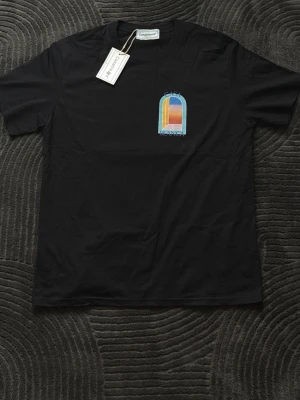 Svart Casablanca t-shirt med tryck - Snygg svart t-shirt från Casablanca med färgglatt grafiskt tryck fram och stort tryck bak. T-shirten har klassisk passform och rund hals. Perfekt för dig som vill sticka ut med stilrena detaljer och cool design.