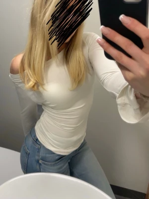 Vit långärmad topp - Snygg vit offshoulder topp med långa ärmar och figurnära passform. Perfekt att styla med jeans för en trendig look. Tunn och stretchig känsla som sitter bekvämt på kroppen.