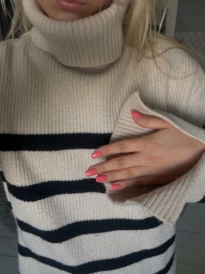 Beige stickad polotröja med svarta ränder -  Ribbstickad beige polotröja med breda ärmar. Tröjan har en oversized passform och är ifrån Zara i storlek S