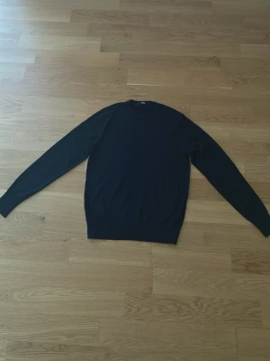 Mörk blå ull tröja - 100% ull. En enkel och stilren mörk blå stickad tröja med rund hals och långa ärmar. Tröjan har ribbade muddar vid ärmslut och nederkant. Perfekt basplagg för lager på lager och funkar till det mesta.