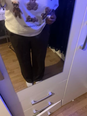 Bruna vida kostymbyxor - Säljer ett par bruna kostymbyxor med rak och vid passform. Byxorna har resår i midjan för extra komfort och är tillverkade i ett mjukt tyg som ger en snygg siluett. Perfekta för en stilren look.