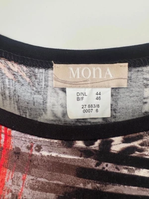 Mönstrad klänning från Mona - Snygg klänning från Mona med abstrakt mönster i svart, rött, orange och vitt. Klänningen har trekvartsärm och en rak passform. Materialet känns mjukt och stretchigt, perfekt för dig som gillar färgstarka plagg med unik design.