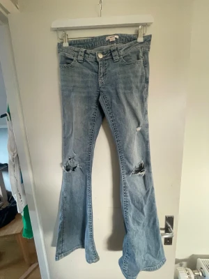 Bootcut jeans med slitningar Gina Tricot - Säljer ett par ljusblå bootcut jeans från Gina Tricot i storlek XS. Jeansen har slitna detaljer och hål vid knäna.