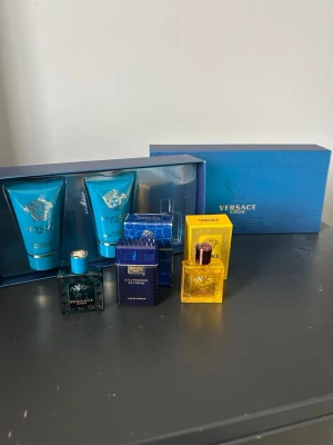 Versace parfymset med flera dofter - Snyggt parfymset från Versace med flera olika dofter i små flaskor. Setet innehåller både blå och gula flaskor samt matchande förpackningar. Medföljer även två blå tuber, troligen duschgel och aftershave balm. Allt kommer i en elegant blå presentask.