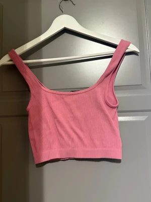 Rosa ribbad linnetopp - Säljer en rosa ribbad linnetopp med breda axelband och croppad passform. Toppen är ärmlös och har en enkel, stilren design som passar perfekt till jeans eller kjol. Materialet känns mjukt och stretchigt. Finns några små fläckar på insidan vid ryggen (sista bilden). Storleken är XS-S men gick inte att lägga in båda 😊