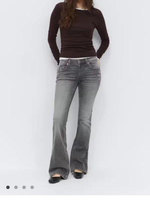 Grå bootcut jeans med broderade fickor - Snygga grå bootcut jeans med broderade detaljer på bakfickorna och klassisk femficksdesign. Jeansen har låg midja och är tillverkade i ett mjukt denimtyg med lätt tvättad look. Perfekta för dig som gillar en avslappnad men trendig stil.