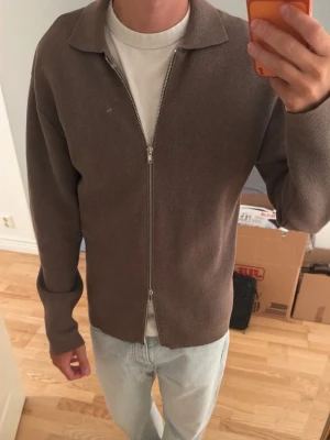 Zip-up kodta - Säljer en stilren brun ziptröja med klassisk krage och långa ärmar, Åhléns egna märke och den är använd max en handfull gånger så skulle klassas som ny enligt mig då det inte finns några tecken på användning. Denna passar både medium och large beroende hur man vill att den ska sitta på kroppen.