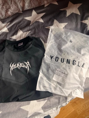 Compression shirt YoungLA S - Snygg svart t-shirt från YoungLA med coolt vitt tryck på bröstet i metallisk stil. Tillverkad i ett lätt och ventilerande material som passar perfekt till träning eller chill. Klassisk passform och rund halsringning. Stk S