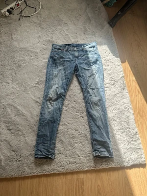 Ljusblå slim fit jeans - Säljer ett par ljusblå slim fit jeans med klassisk femficksdesign och dragkedjegylf. Jeansen har en något tvättad look och raka ben. Perfekta till en avslappnad stil och passar till det mesta i garderoben. Dom har även snygga fades på benen.
