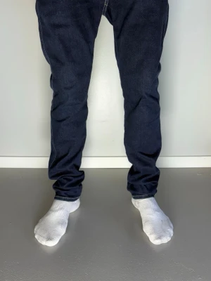 Mörkblå Replay jeans herr - Tjeeena! Säljer nu dessa riktigt snygga mörkblå replay jeans med rak passform och klassiska sömmar. Jeansen har en enkel design utan slitningar och är tillverkade i ett robust denimtyg som passar perfekt till vardagslooken. Perfekta för dig som gillar stilrena och tidlösa jeans.