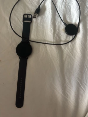 Samsung smartwatch - Snygg svart smartklocka med rund urtavla och silikonarmband. Klockan har en modern design och kommer med magnetisk USB-laddare. Perfekt för dig som vill ha koll på notiser och hälsa direkt på handleden. Kan göra väldigt mycket på den ä, SMS, ringa, puls, kalkylator, musik osv.