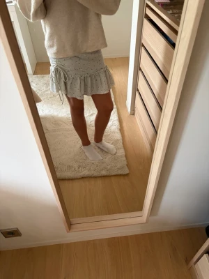 Ljusblå kortkjol med volang och snörning - Supersöt ljusblå kortkjol med små blommor, volangkant och snörning i sidorna. Kjolen har en feminin och trendig look som passar perfekt till stickade tröjor eller crop tops. Materialet känns lätt och flowy, perfekt för varmare dagar.🩷passar mig som brukar ha xs!💕