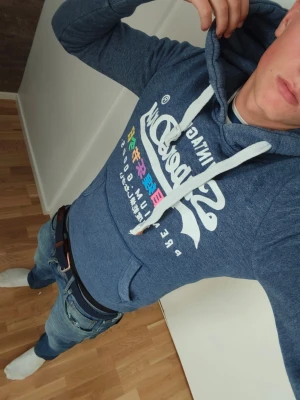 Superdry hoddie  - Fin mörkblå superdry hoddie i väldigt bra skick modellen på bilden är 177cm och den passar bra men kanske något liten 