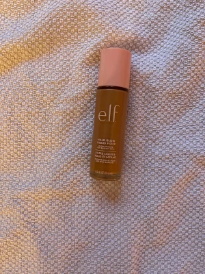 e.l.f. Halo Glow Liquid Filter foundation - e.l.f. Halo Glow Liquid Filter foundation i en varm brun nyans. Kommer i en cylinderformad glasflaska med rosa lock och stor applikator. Ger glowig finish och kan användas både som foundation eller highlighter. Perfekt för dig som vill ha en naturlig lyster. Mycket kvar
