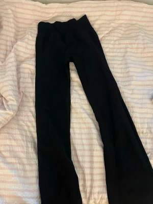 Svarta yoga pants från ICIW - Säljer ett par svarta yoga pants från ICIW med bootcut-ben. De har hög midja och är gjorda i ett stretchigt sportigt  material som sitter skönt. Perfekta för dig som gillar en clean och enkel look med lite vidare ben nertill.