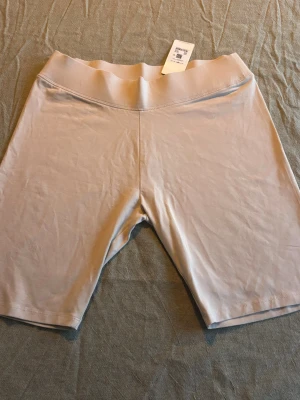 Beige cykelshorts, essence bike shorts L - Säljer ett par beige cykelshorts med bred resår i midjan. De är midwaist och har en enkel, stilren design utan synliga detaljer. Perfekta för träning eller som basplagg till vardags. Materialet känns mjukt och stretchigt. Helt nya med prislapp kvar.