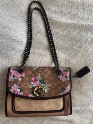 Coach Parker Shoulder Bag Signature Canvas With Unique Blossom Print  - Säljer min äkta Coach Parker Shoulder Bag i Signature Canvas med Blossom Print 🤎  Svårhittad och utgången modell från ca 2018–2019 med ikoniskt Signature Canvas, blommigt Blossom-mönster och fina detaljer. Perfekt statement-väska till både vardag och fest.  ✨ Äkta Coach ✨ Justerbart axelband ✨ Utgången modell  Fint skick med små användningstecken och lätta märken på insidan (se bilder). Bild på etiketten inuti finns och fler äkthetsbilder kan skickas vid intresse. 