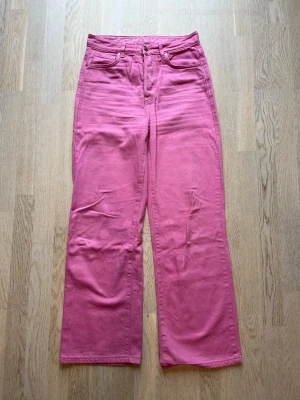 Rosa raka jeans med hög midja - Säljer ett par snygga rosa jeans med raka ben och hög midja. Jeansen har klassisk femficksdesign och stängs med knappar. Materialet är kraftigt bomullstyg som ger en skön och avslappnad look. Tveka inte på att skriva en fråga eller be om fler bilder.🌸🌸