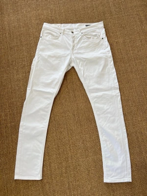 Vita raka jeans från Dondup - Snygga vita jeans från Dondup med rak passform och klassisk femficksdesign. Jeansen har knappgylf och är tillverkade i bomull med en liten stretch för extra komfort. Perfekta för en clean och fräsch look.