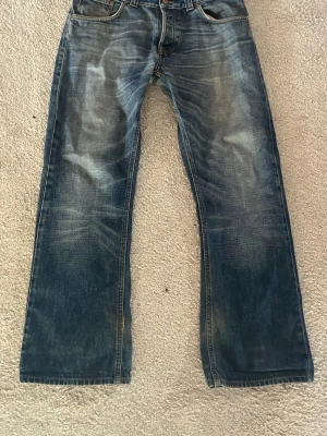 Nudie regular ralf - Säljer ett par nudie regular ralfs i storlek 33/32 med en skit snygg bootcut fit, de är smått smutsiga med benen som lätt går bort vid tvätt, de har även slitningar längst ner vid benen som kan lagas gratis vid inlämning på nudie butik. Tveka inte att fråga om du undrar något👍