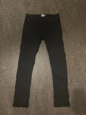 Svarta slim jeans med hög midja - Säljer ett par svarta lager157 jeansmed hög midja och smal passform. Jeansen har klassiska bakfickor och bälteshällor. Perfekta till en avslappnad eller trendig look. Materialet känns som bomull med lite stretch. 