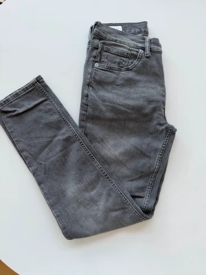 Grå jeans från ZARA - Snygga grå jeans från ZARA med klassisk femficksdesign och normal midja. Jeansen har en tvättad look och är perfekta för en avslappnad stil. Tillverkade i ett stretchigt material som sitter skönt hela dagen.