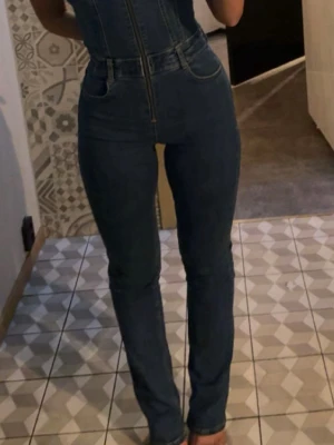 Blå denim jumpsuit  - Denim jumpsuit från pull & bear. Dragkedja framtill hela vägen upp. Materialet är stretchigt jeans-tyg som sitter tight och formar kroppen