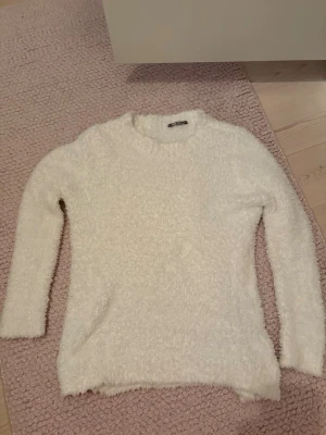 Vit fluffig stickad tröja Lindex - Mysig vit stickad tröja från Lindex i storlek 170. Tröjan är fluffig och har rund halsringning samt långa ärmar. Väldigt skön och mjuk, perfekt till mysiga kvällar.