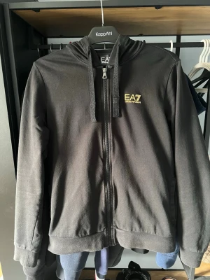 EA7 Emporio Armani hoodie - Säljer en EA7 Emporio Armani zip hoodie i mycket bra skick, använd ett par gånger. Säljer då den inte kommer till användning längre. Vid fler bilder/frågor är det bara att höra av sig. Pris kan diskuteras!