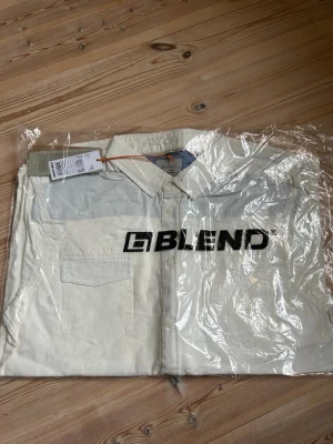 Vit skjorta från Blend, storlek M - Klassisk vit skjorta från Blend i storlek M. Skjortan har en bröstficka, knappar framtill och en stilren krage. Perfekt för dig som gillar enkel och clean stil. Nypris 499kr