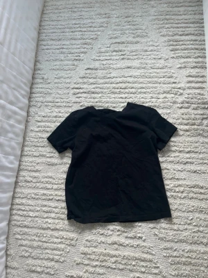 Svart basic t-shirt unisex - En enkel svart t-shirt med rund hals och korta ärmar. Passar perfekt till alla typer av outfits och har en klassisk rak passform. Tillverkad i mjukt material för skön känsla hela dagen.