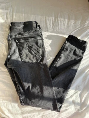 Chasin' jeans - Snygga grå slim fit jeans från Chasin' med slitna detaljer och flera revor framtill. Jeansen har klassisk femficksdesign och är tillverkade i denim med en cool tvättad look. Perfekta för en avslappnad och trendig stil.