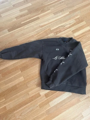 Mörkgrå sweatshirt Le Otte 039 - Cool mörkgrå sweatshirt med tryck från Le Otte. Framsidan har vit text och grafiska detaljer, medan baksidan har ett stort '039'-tryck och mindre text nertill. KAN DISKUTERA PRIS!!