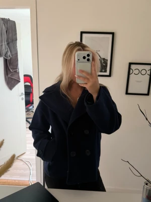 Mörkblå kappa  - En mörkblå kappa från design by si, perfekt nu till hösten/vintern. Har använts en vinter tidigare så den är i bra skick. I storlek m/l