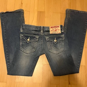 True religion jeans - Lågmidjade blåa True Religion jeans i skorlek 26. De är lite ljusare i verkligheten än på bild. Mycket bra skick förutom lite slitage längst ner. Midjemått tvärs över: 35cm Innerbanslängd: 78cm Bootcut bredd: 22cm. Tvättar innan skickar och skickar samma dag eller nästa dag efter köpt!