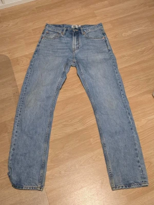 Ljusblå jeans billiga - Säljer ett par klassiska ljusblå jeans med rak passform och fem fickor. Jeansen har normal midja och är tillverkade i denim. Perfekta för en avslappnad och tidlös stil. Från lager 157