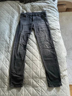 Mörkgrå slim fit jeans - Snygga mörkgrå slim fit jeans med klassisk femficksdesign och normal midja. Jeansen har en lätt tvättad look och smala ben som ger en modern siluett. Perfekta för dig som gillar en stilren och enkel look. 