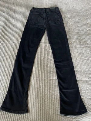 Svarta bootcut jeans med utsvängda ben - Säljer ett par svarta bootcut jeans med utsvängda ben. Jeansen har hög midja och är tillverkade i ett mjukt denimtyg som sitter snyggt. Perfekta till en stickad tröja eller en topp.